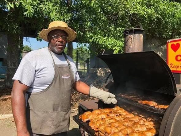 John Hughes tending a pit full of chicken quarters
